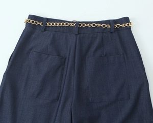 Détail du short en jean bleu foncé avec une ceinture chaîne dorée et poches arrière