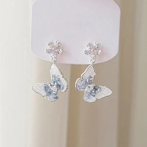 Detail showing blue and white crystal butterfly earrings with silver flower studs