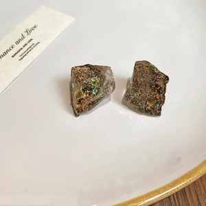 Detailed close-up of irregular resin stud earrings filled with gold foil and sequins
