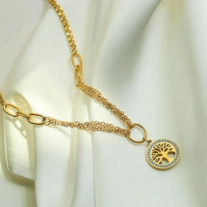 Gold Tree of Life pendant necklace with cubic zirconia on a white silk background