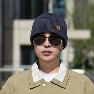 Detail of dark blue ribbed knit beanie with leather logo patch and outdoor gear