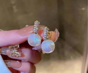 Macro shot of gold hoop earrings with pavé zircons and aurora iridescent pearls