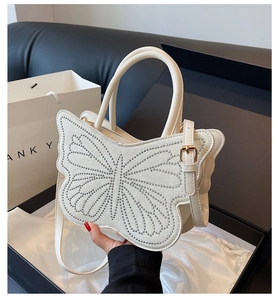 Close-up of a white butterfly tote bag with silver rhinestones and golden metal hardware