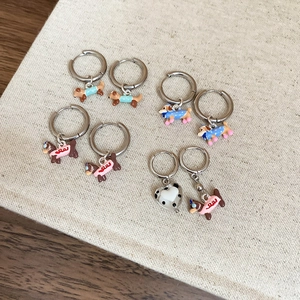 Detailed view of colorful enamel dachshund and heart hoop earrings on woven fabric