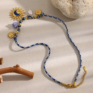 Detail of 18K gold sun moon pendants on blue woven rope necklace with pearl charm