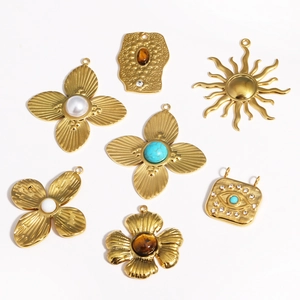 Flat lay of seven gold vintage pendants with cat-eye stones, pearls and turquoise charms