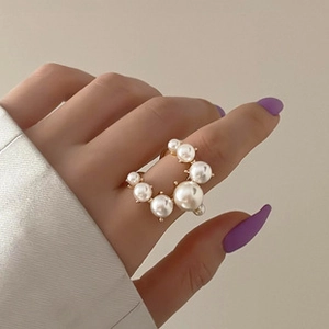Détail de la bague en grappe de perles dorées portée à la main pour un style minimaliste