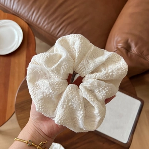 Close-up of white lace embroidery scrunchie with delicate floral patterns and mesh texture