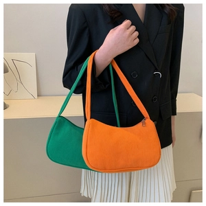 Close-up of orange and green corduroy crescent shoulder bags worn by a model