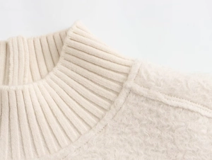 Close-up of soft beige knit sweatshirt showing plush fleece texture and neckline detail