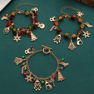 Golden Christmas bracelet set with Santa, tree, and snowflake charms on green background