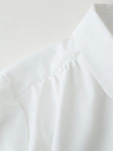 Detail of white resort style shirt featuring classic collar and pleated shoulder seams