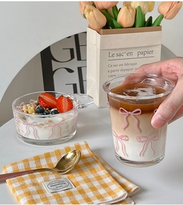 Detail of a clear glass cup and salad bowl set featuring pink ribbon patterns