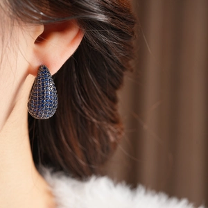 Close-up of vintage teardrop earrings with deep blue zircons worn by a model