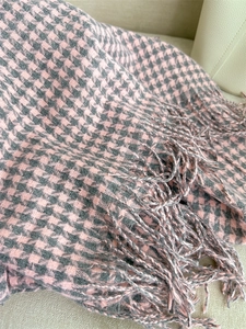 Detailed macro view of pink and grey houndstooth scarf texture with fringe detail