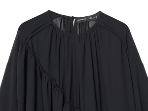 Detail of black chiffon blouse neckline with button closure and delicate pleated texture