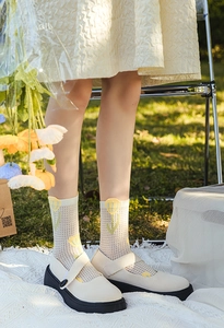 Detailed view of white mesh socks with yellow tulip pattern and platform Mary Jane shoes