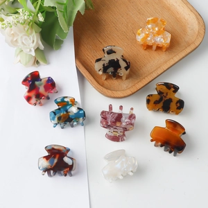 Collection of 3cm tortoiseshell and marble mini hair claws on a rustic wooden tray