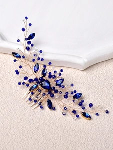 Close-up of handmade bridal hair comb with emerald blue crystals and gold wire leaves
