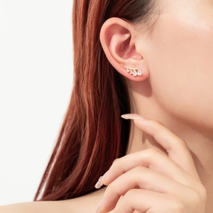 Elegant gold drop earrings with four pear-shaped crystals on model with white background