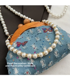 Detail of light blue denim mini bag with pearl handle and butterfly sequin embroidery