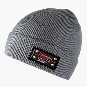 Grey ribbed knit beanie with red FASHION label and metal studs on a white background