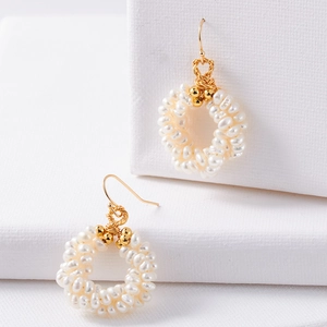 Elegant freshwater pearl hoop earrings with gold hooks on a white textured surface