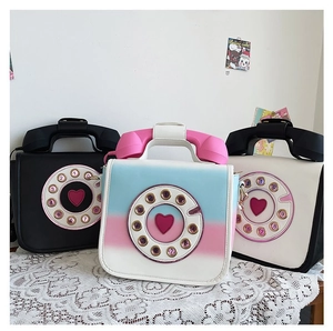 Novelty vintage rotary phone crossbody bags in multiple colors on a lace tablecloth