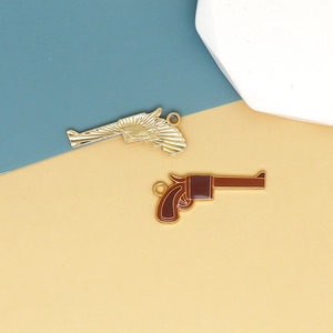 Macro shot of western style cowboy gun charms in gold metal and brown enamel finish