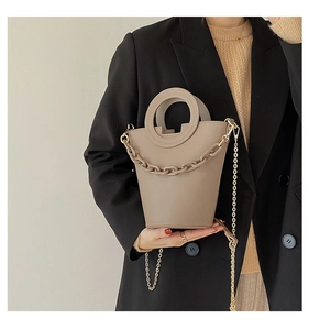 Fashionable khaki bucket bag with circular handle and chain strap shown on a model