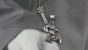 Detailed view of silver skull hand guitar pendant with sharp metallic texture