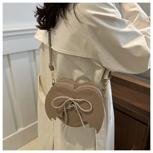 Close-up of heart-shaped bat wing crossbody bag with lace-up detail worn by a model