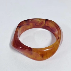 Macro detail of amber marble resin bangle with smooth finish and tortoiseshell pattern