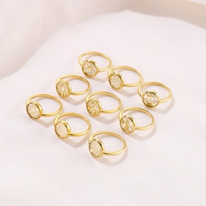 Set of nine gold geometric zircon rings with hollow floral patterns on beige background