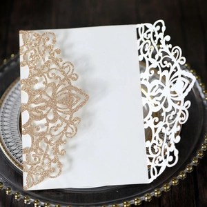 Detail of rose gold glitter laser-cut floral wedding invitation on a decorative plate