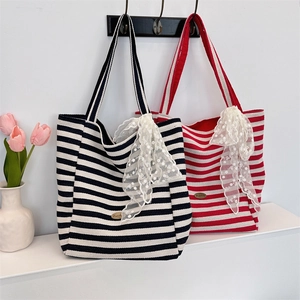Close-up of high-capacity striped canvas tote with lace bow and metal logo detail