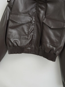 Detail of dark brown faux leather jacket featuring elastic hem and precise stitching