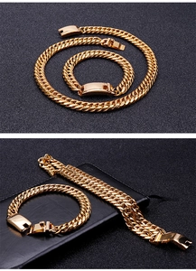 Macro shot of gold stainless steel curb chain necklace and bracelet set on black background