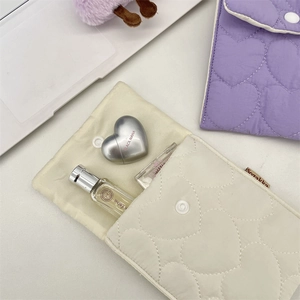 Close-up of quilted heart pattern storage bags in cream and purple with snap button detail