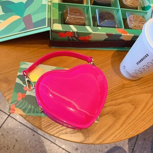Detail of rose red heart-shaped jelly bag with glossy finish and gold hardware accents