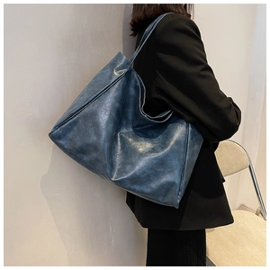 Macro detail of retro blue leather tote bag showing large capacity and side stitching
