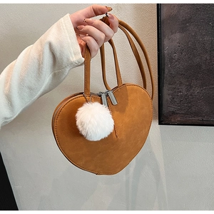 Detailansicht der herzförmigen Wildledertasche in Karamell mit flauschigem Bommel
