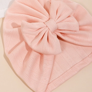 Détail d'un bonnet en tricot rose respirant pour bébé avec un grand nœud décoratif