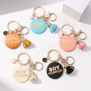 Detail view of colorful BOY MAMA leather keychains with stylish tassels and gold charms
