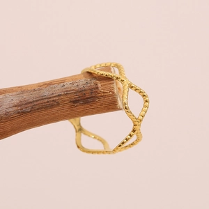 18K gold plated stainless steel wave ring with a twisted open design on wood