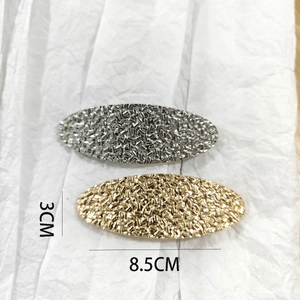 Detail view of gold and silver textured oval hair clips with 8.5cm x 3cm dimensions