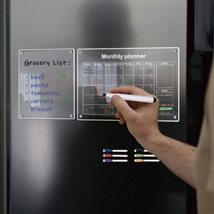 Close-up of magnetic acrylic monthly planner and markers on a black refrigerator