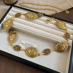 Detail of vintage gold waist chain with textured oval links and rose flower charm