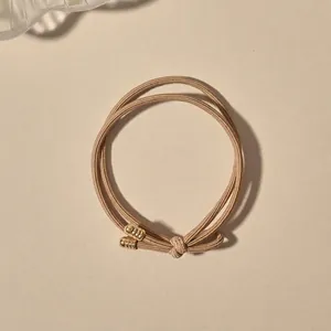 Close-up of khaki braided elastic hair tie with knotted detail and golden metal tips