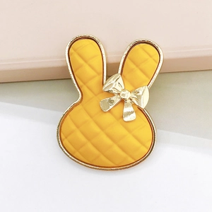 Macro detail of yellow bunny charm with quilted texture and golden metal accents